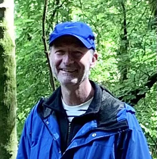 Headshot of Bob O'Connor in a blue cap and coat in the forest