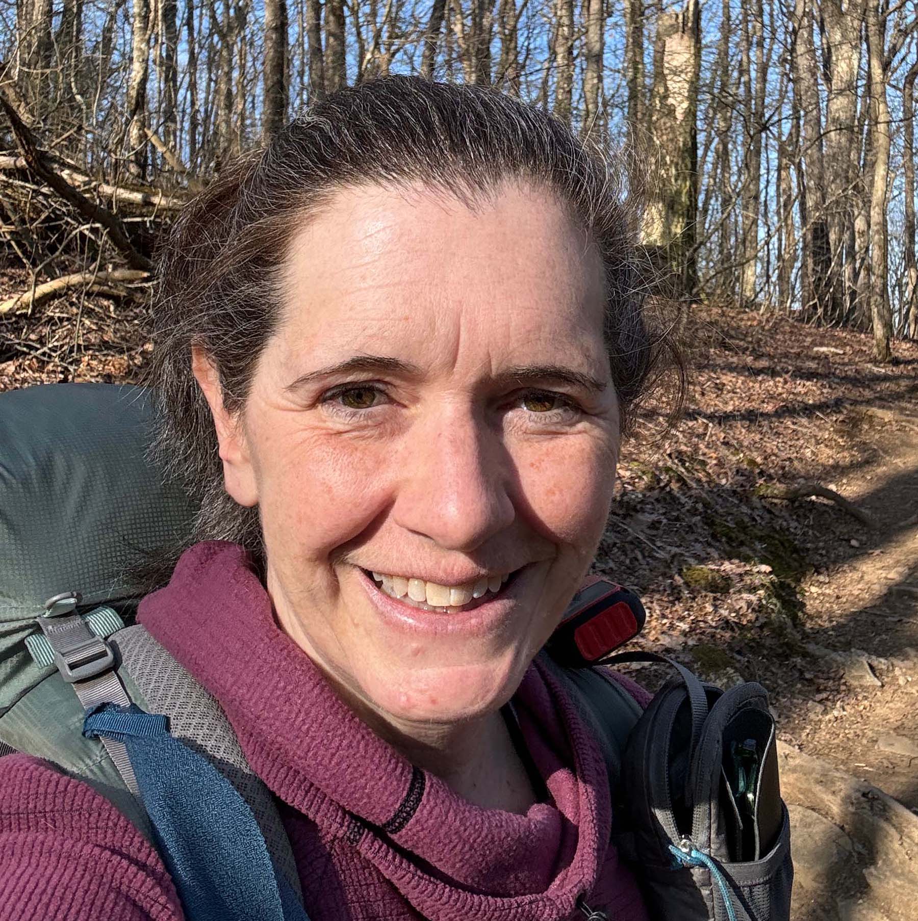 Headshot of Carrie McMillen in the forest on a sunny day